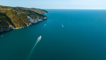 Aerial view of a mountain with a dense forest that descends to the sea. Boats crossing the sea....