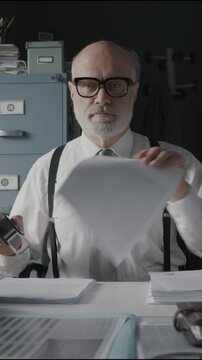 Bored apathetic office worker doing a repetitive task, he is stamping a pile of documents