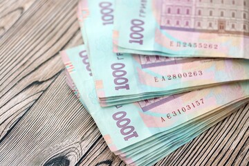 Big amount of ukrainian new one hundred hryvnia money bills with modern design on wooden background. Financial concept, business