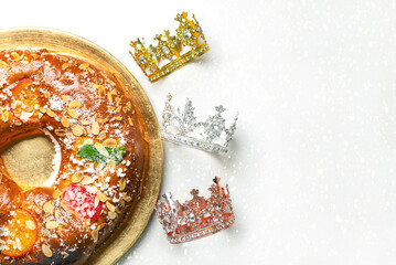 Top view of Roscon de reyes on a golden plate with crowns of the wise men and space for text. Kings...