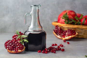 Glass bottle of pomegranate sour sauce with fresh ripe whole and split pomegranate fruit (Turkish...