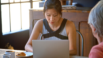 Female Customer In Coffee Shop Sitting At Table Using Laptop Computer