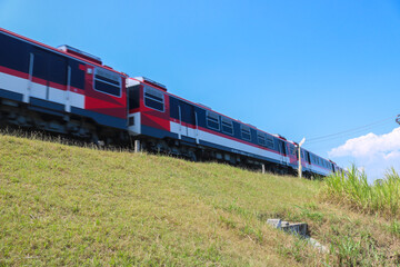 A high-speed train by on the tracks through the countryside with views of grasslands and blue skies. Kereta Indonesia commuter line