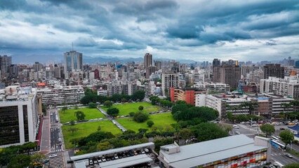 Aerial view of Taipei showcasing buildings and green spaces under a cloudy sky