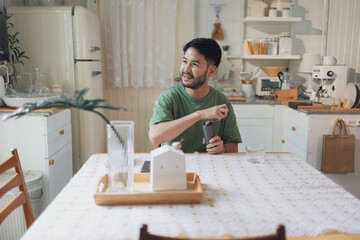 Smiling Man Grinding Coffee by Hand in Cozy, Vintage-Inspired Kitchen with Natural Light