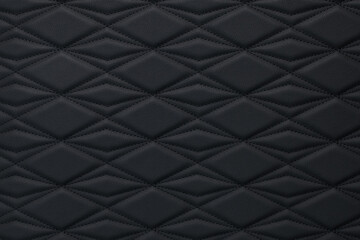 A close-up of black leather upholstery with diamond-shaped stitching.