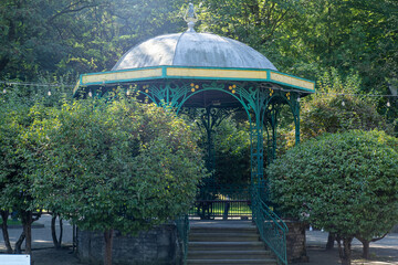 Gazebo in a green park. Bench pavilion.