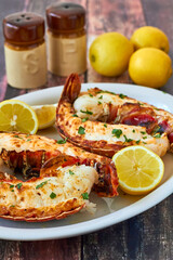 broiled rock lobster tails served with butter and fresh lemon on a white plate