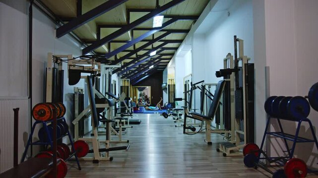 Exploring a spacious gym with various workout equipment and training areas in the late evening