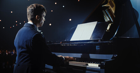 On a Dimly Lit Concert Stage, Male Pianist Delivers an Emotional Improvisation on a Grand Piano....