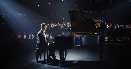 On a Dimly Lit Concert Stage, Male Pianist Delivers an Emotional Improvisation on a Grand Piano. Each Note Resounds Through the Concert Hall, Holding the Excited Audience Spellbound