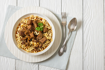 pasta rings topped with braised meat in bowl