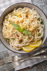 Pasta with creamy ricotta cheese, plenty of fresh lemon, and a generous sprinkle of Parmesan cheese closeup on the plate on the table. Vertical top view from above