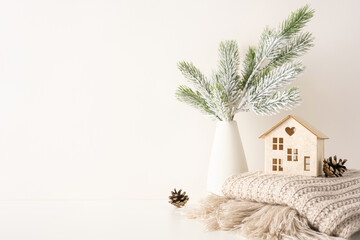 Minimalist side view Scandinavian style decor featuring a vase with snowy pine branches, a small...