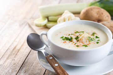 Cauliflower soup in bowl on wooden table. Copy space