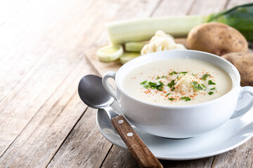 Cauliflower soup in bowl on wooden table. Copy space