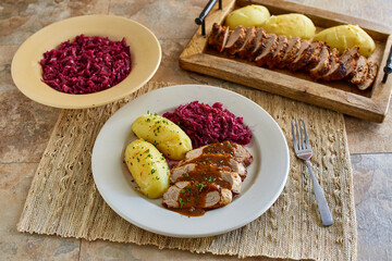 pork shwienbraten served with boiled potatoes and sauteed red cabbage