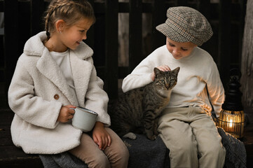 A boy and a girl sit on a blanket in nature, enjoying a retro-style picnic. They hold a lantern and sip hot tea, with a basket of bread beside them, and cat with The warm, nostalgic atmosphere capture