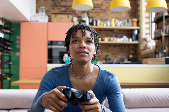 Young adult female playing video game sitting on floor in loft apartment