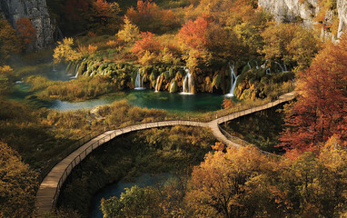 A wooden boardwalk winds through the autumn foliage of Plitvice Lakes National Park in Croatia, with waterfalls and trees in warm hues of orange and red.