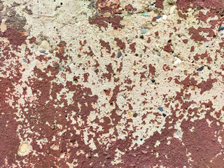 Textured wall surface revealing layers of peeling paint and exposed materials in an urban setting
