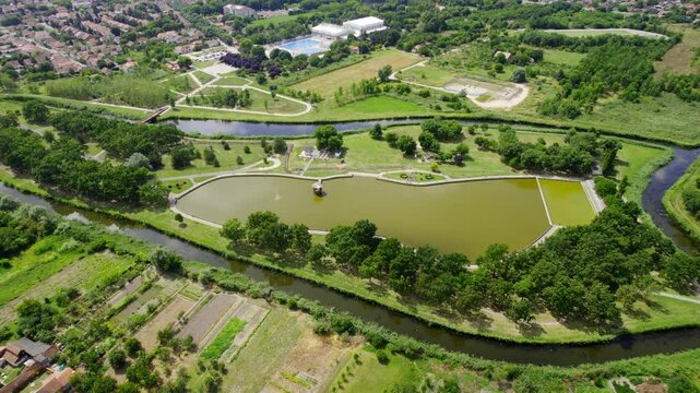 Scenic aerial view of a serene park with a pond and lush greenery on a sunny day