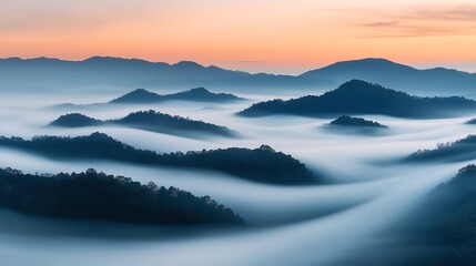 Fototapeta premium Mountain landscape with misty valleys and rolling hills at sunrise, showcasing layers of fog and silhouetted peaks against a colorful sky.