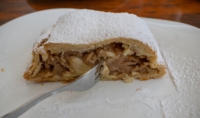 piece of apfelstrudel , apple pie,  on a white plate with a fork ;Austrian pastries