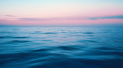 Obraz premium Serene ocean view at sunset. Calm water reflects a pastel pink and blue sky. Peaceful and tranquil seascape perfect for backgrounds or travel themes.