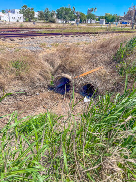 Two side-by-side concrete stormwater culverts under train railroad tracks