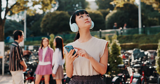 Headphones, phone and thinking with Japanese student in park for streaming, University campus and online playlist. Music, vision and education podcast with woman and mobile in Japan for college