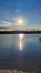 Golden sunset reflecting on the calm waters of the Dnipro River, with the Kyiv skyline and Motherland Monument in the distance