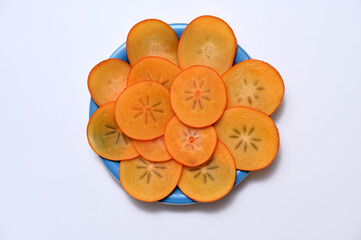 persimmon fruit sliced ​​on a plate isolated on white background