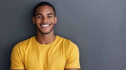 Smiling Young Man in Yellow T-Shirt Against Gray Background