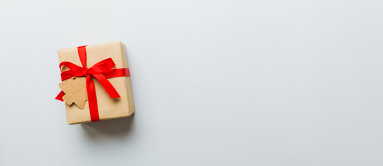 wrapped christmas or other holiday handmade present in paper with colored ribbon. Present box, decoration of gift on colourfull table, top view with copy space