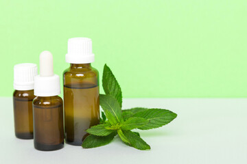 Natural Mint Essential Oil in a Glass Bottle. organic cosmetics with herbal extracts of mint on colored background