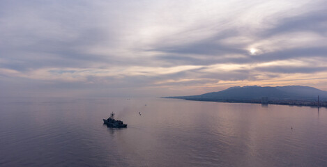Tranquil sunset seascape with boat and vibrant sky reflections; serene coastal landscape ideal for themes of peace and relaxation.