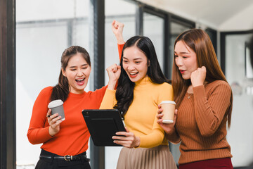 Excited women celebrating success while using tablet in modern office