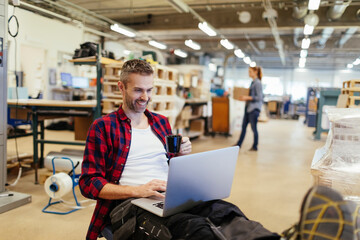 Fototapeta premium Young man using a laptop while working in a printing press office