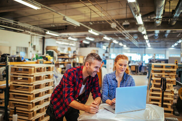 Young man and young woman using a laptop while working in a printing press office