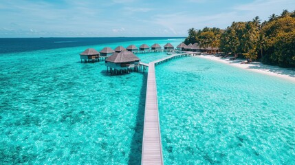Obraz premium A stunning aerial view of a tropical beach with overwater bungalows, clear turquoise waters, and lush green trees under a bright blue sky.