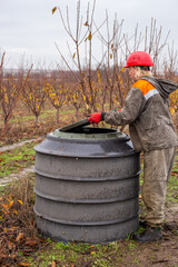 Assembled water well body. A worker installs a water well for a pumping station in an orchard