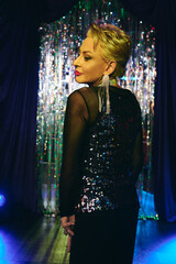 A drag queen wows the crowd with stunning makeup and a dazzling outfit at a festive show.