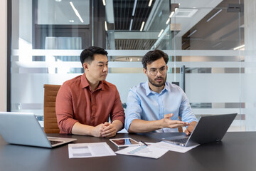 Business professionals in meeting discussing project. Colleagues collaborating over laptop,...