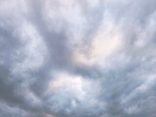 the grey overcast sky. A sweeping pattern of clouds evolving as an intricate background pattern. Cloudscape scenery, overcast weather.