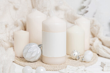 Pillar candle with label near white sweater and wooden Christmas decor, mockup