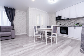 modern apartment interior design kitchen and hall. large dining table with chairs. interior in light and gray colors