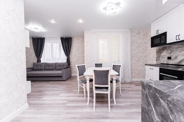 modern apartment interior design kitchen and hall. large dining table with chairs. interior in light and gray colors