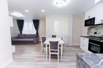 modern apartment interior design kitchen and hall. large dining table with chairs. interior in light and gray colors