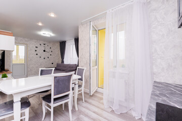 modern apartment interior design kitchen and hall. large dining table with chairs. interior in light and gray colors
